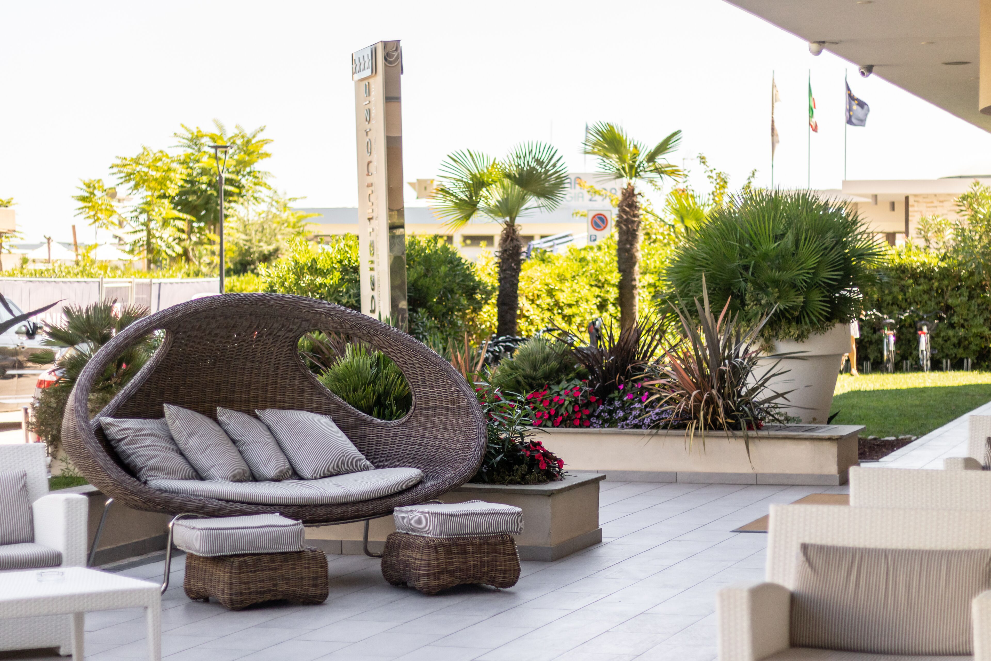 An outdoor seating area with wicker furniture, a hanging chair, and potted plants.