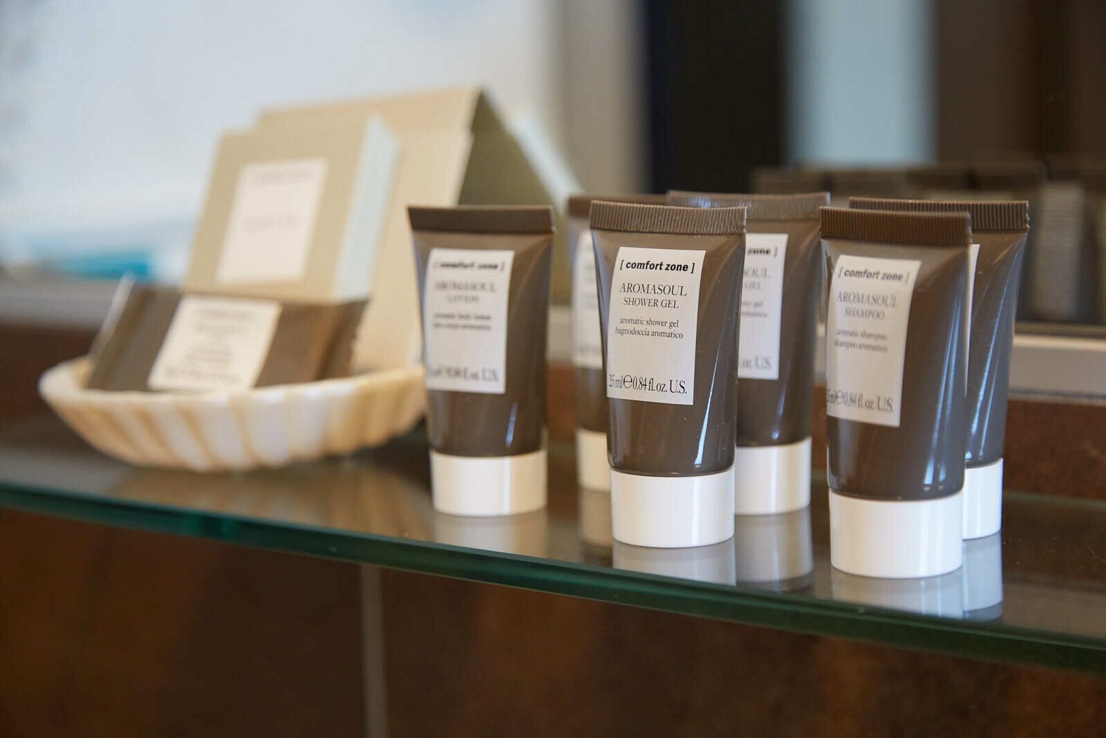 Une sélection de produits d'aromathérapie, notamment du gel douche et du shampooing, est présentée sur une étagère en verre.