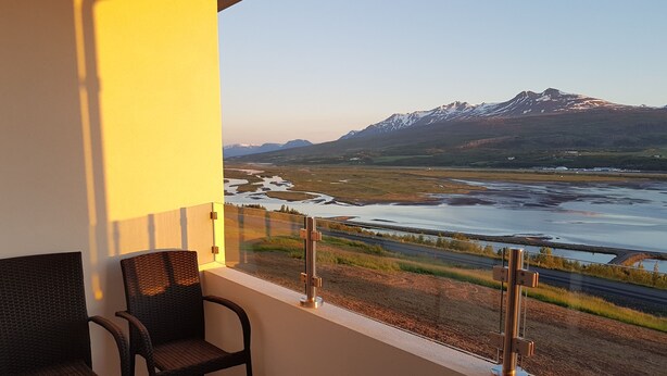 A balcony with a view of a mountainous landscape and a river. - Hafdals Hotel (Akureyri)