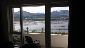 A room with a large window overlooking a lake and mountains. - Hafdals Hotel (Akureyri)