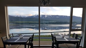 A dining area with a large window overlooking a lake and mountains. - Hafdals Hotel (Akureyri)
