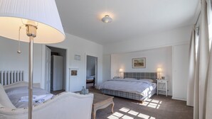 Una habitación de hotel con una cama, una silla, una mesa, una lámpara y un radiador.