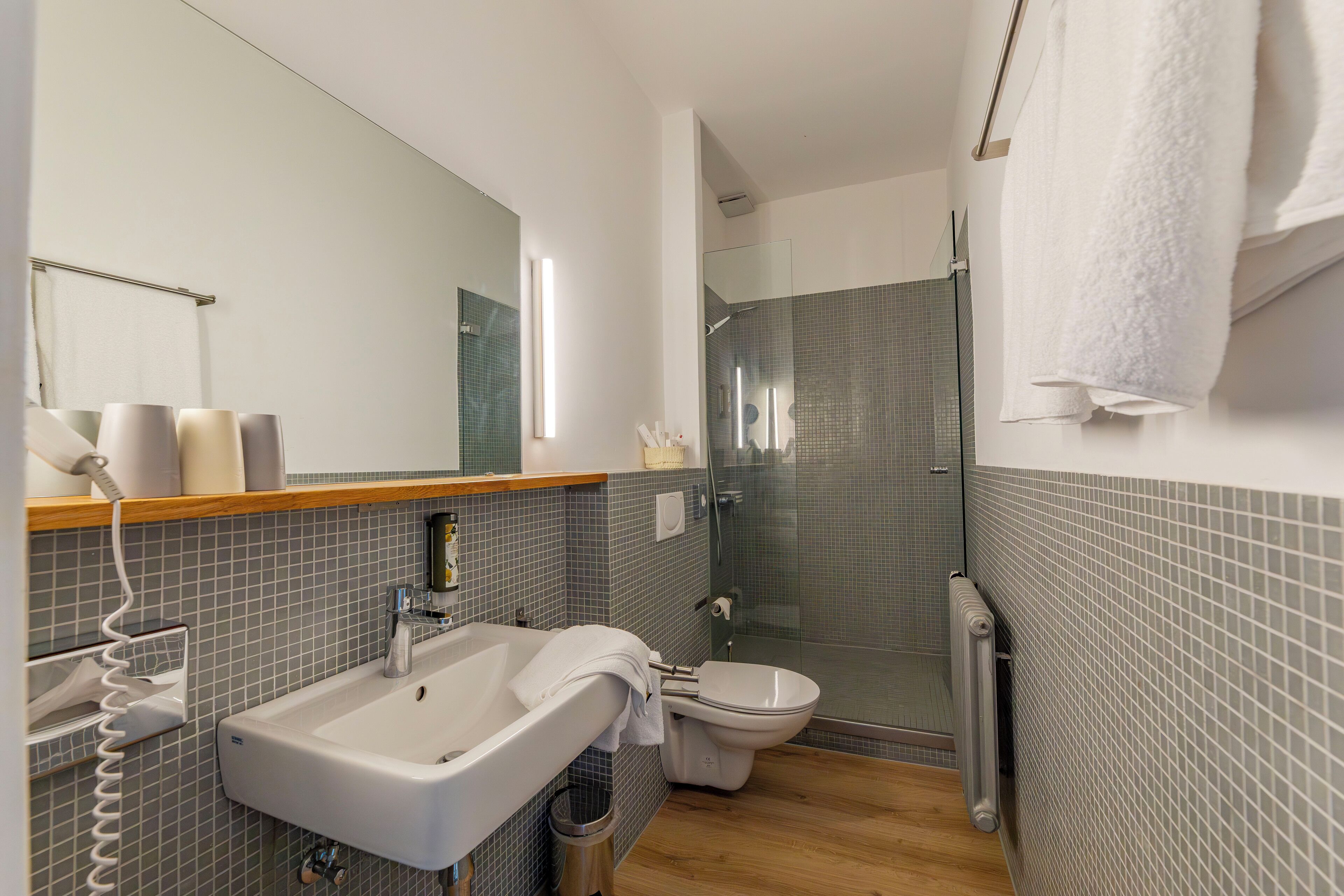A modern bathroom with a glass-enclosed shower, a white sink, and a toilet.
