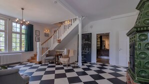 A hotel lobby with a checkered floor, a staircase, a chandelier, and a green decorative piece.