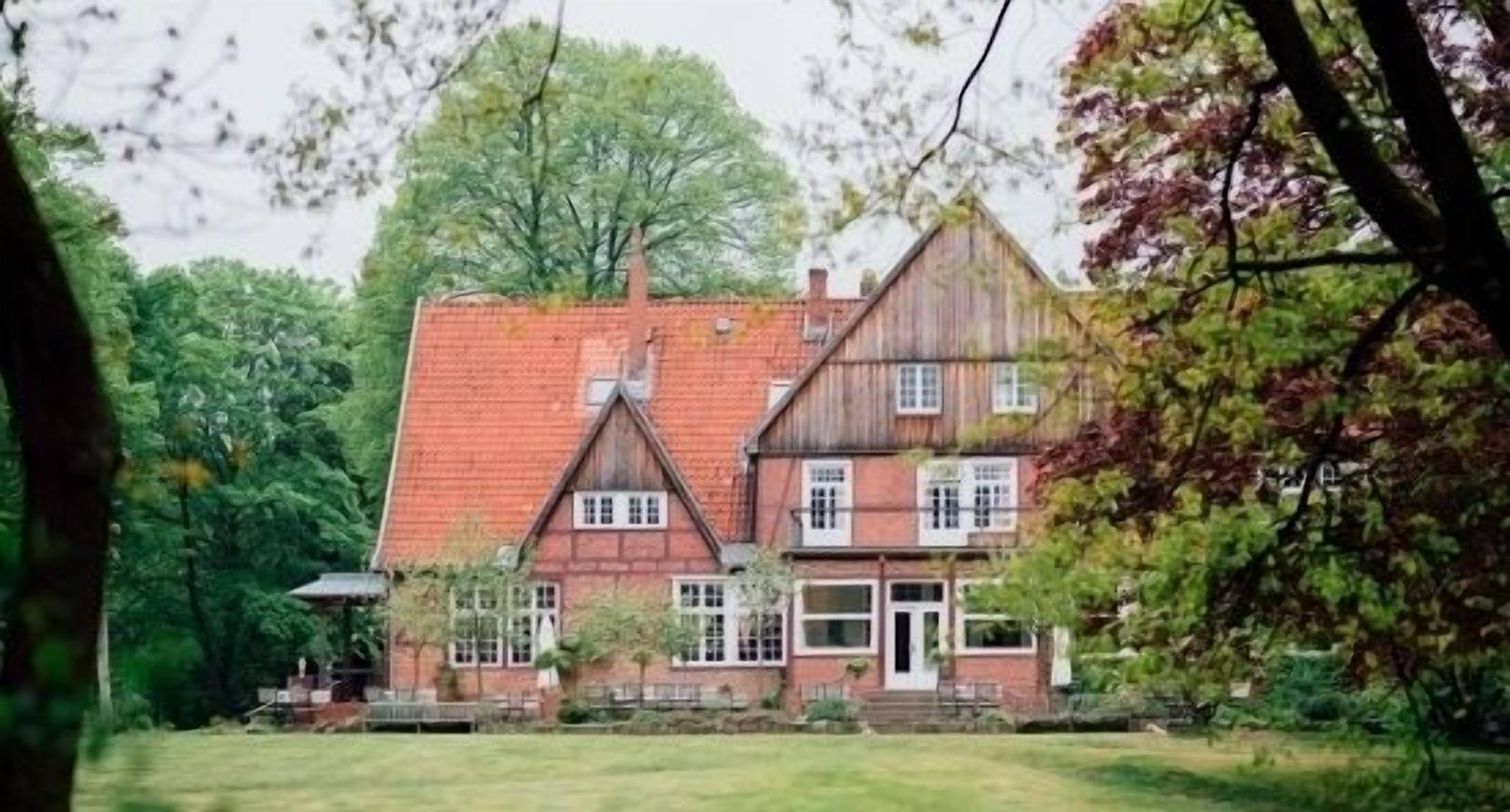 Een herenhuis met een rode dakbedekking en een gevel van baksteen.