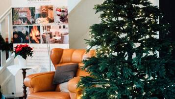 A checkered floor, a Christmas tree, a leather armchair, and a staircase with garlands.