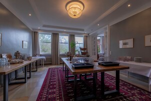 A spacious room with a long wooden table, a red patterned rug, and a chandelier.