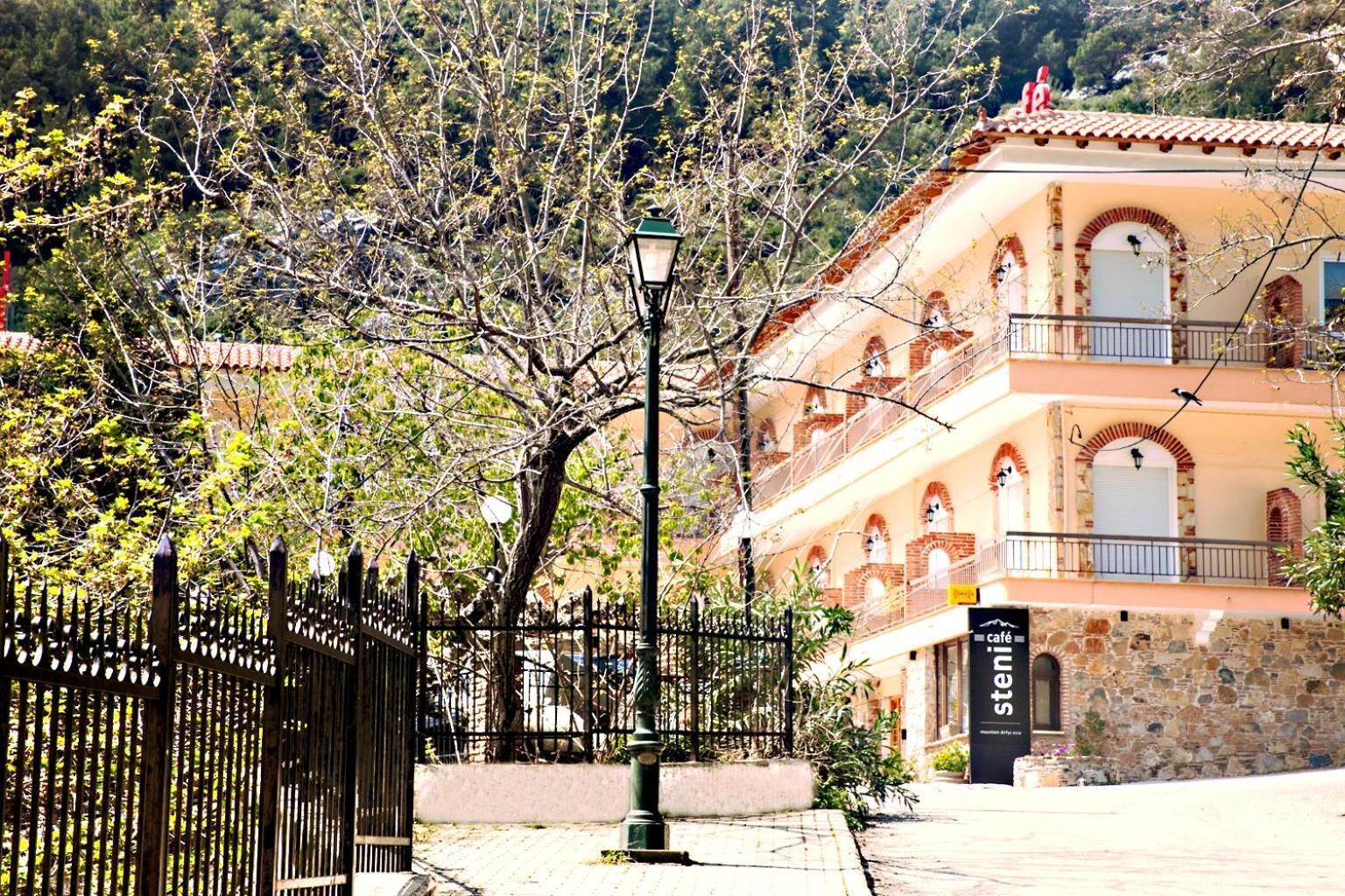 A building with a stone facade, multiple balconies, and a cafe sign.