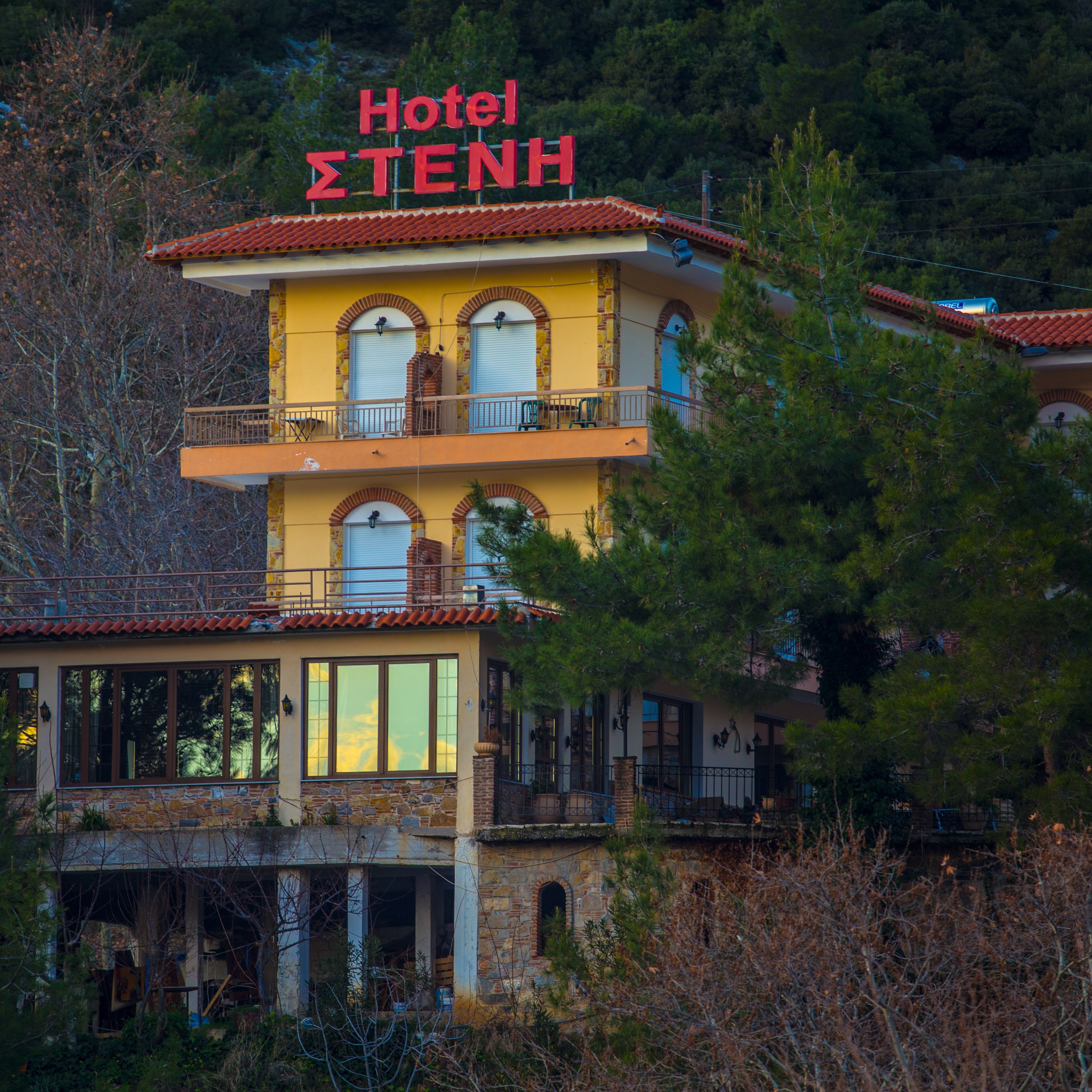 Un edificio de dos plantas con un letrero que dice 'Hotel ΣΤΕΝΗ'.