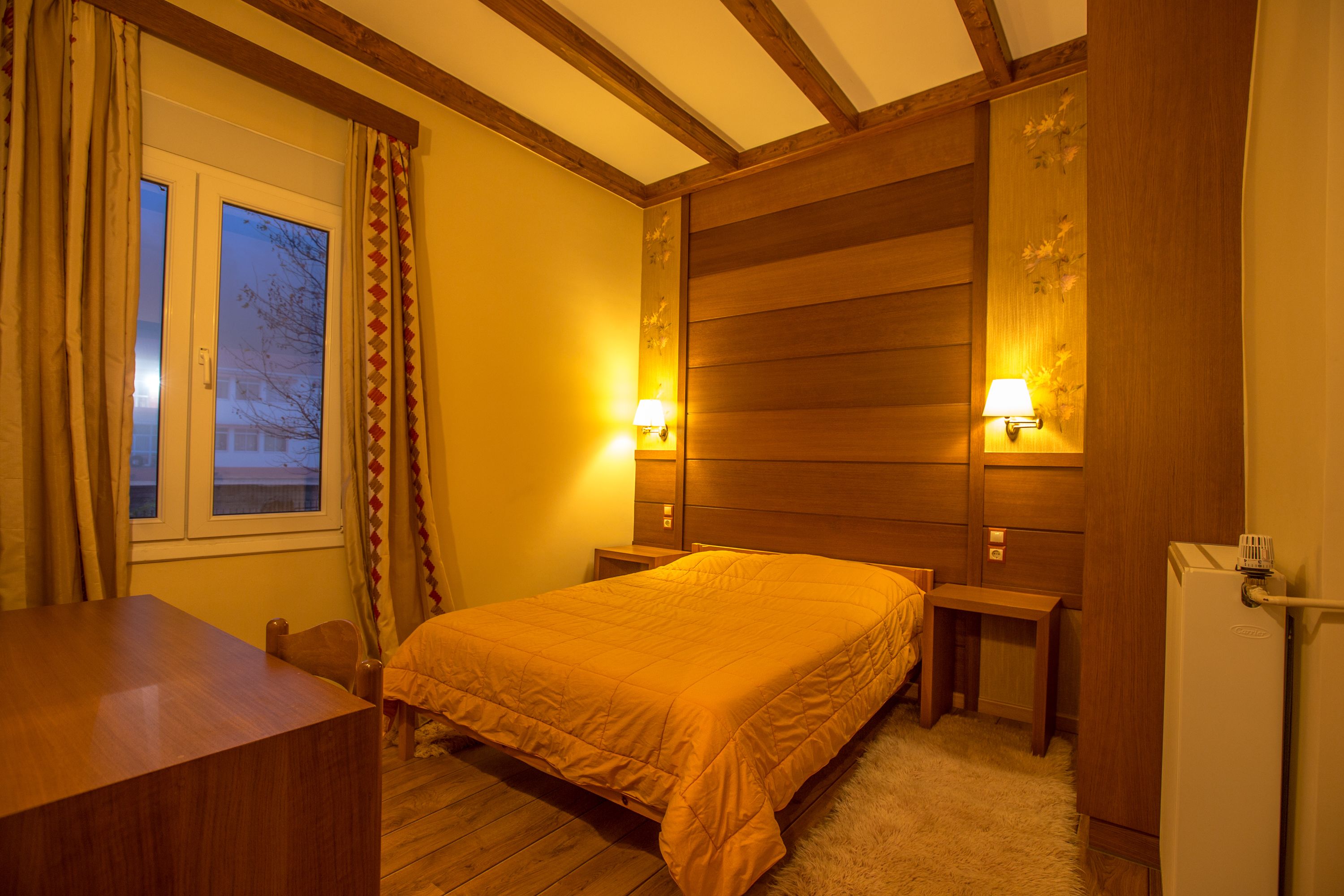 Una habitación con una cama de madera, un escritorio y un refrigerador pequeño.