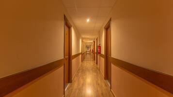 A long, narrow hotel corridor with wooden floors and doors on both sides.