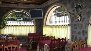 A restaurant with stone walls, arched windows, and wooden tables and chairs. - Posada de los Consules Consuegra (Consuegra)