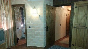 A room with a bed, a television, a wooden door, and a light fixture. - Posada de los Consules Consuegra (Consuegra)