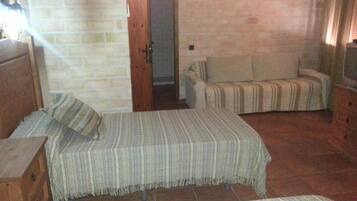 Una habitació amb dos llits, un armari de fusta, una televisió i una paret de maó.