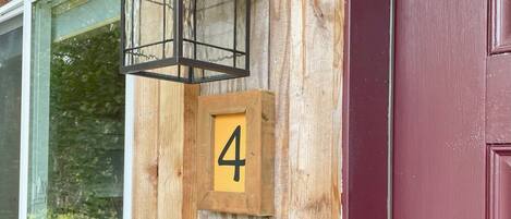 A wooden cabin with a black lantern, a number 4 sign, and a chalkboard sign reading "Cabin 4 Welcome Chen".