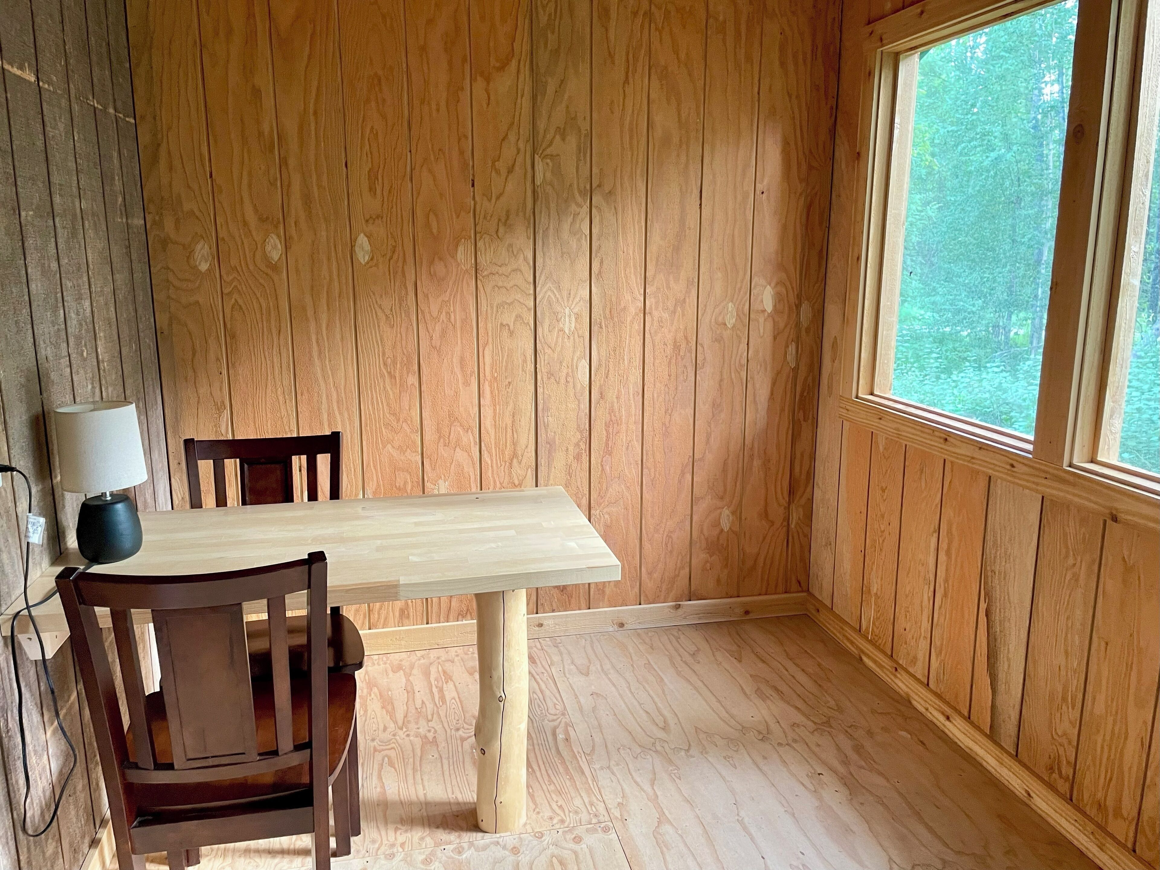 A room with wooden paneled walls, a wooden table, and a chair.