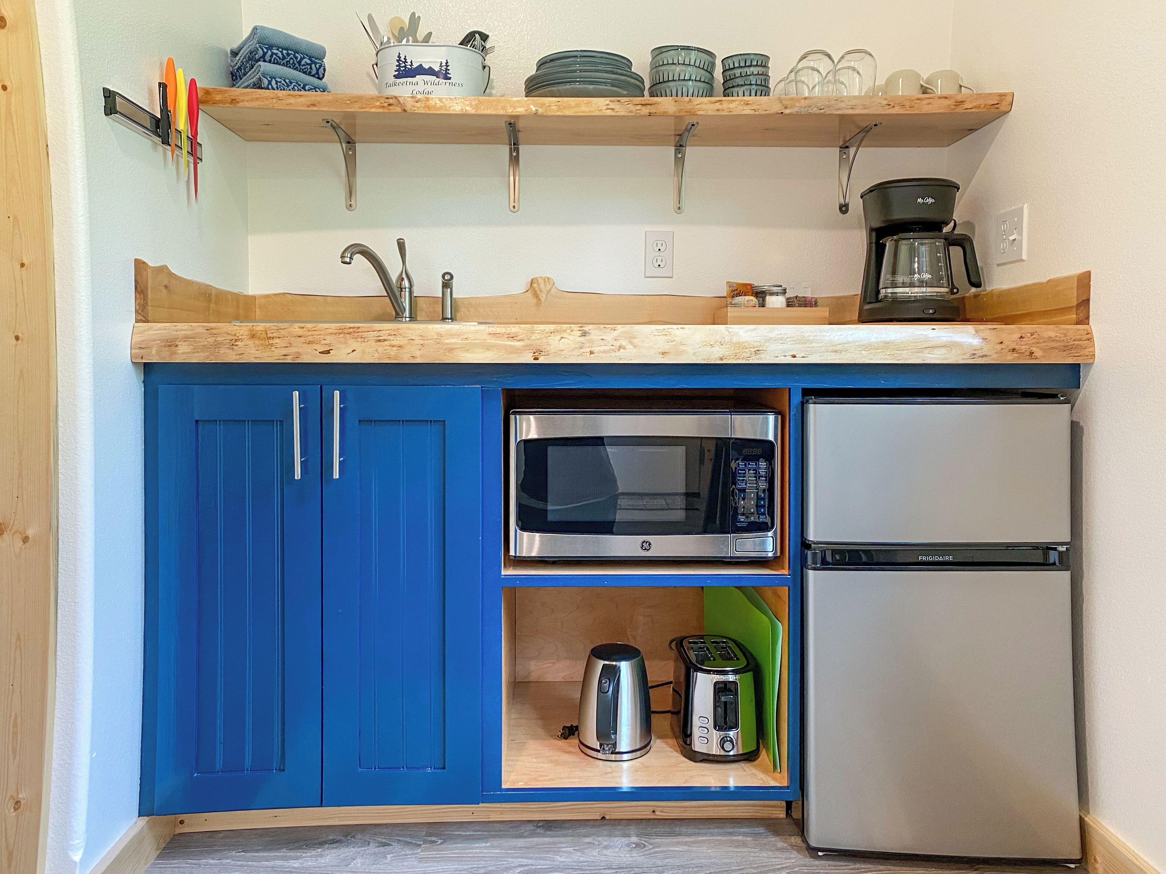 A compact kitchen with blue cabinets, a microwave, a toaster, and a coffee maker.
