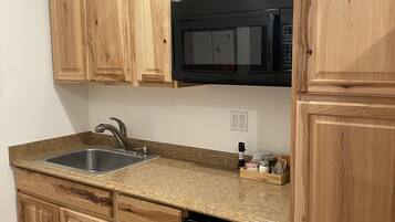 A kitchen with wooden cabinets, a stainless steel sink, a microwave, and a dishwasher.