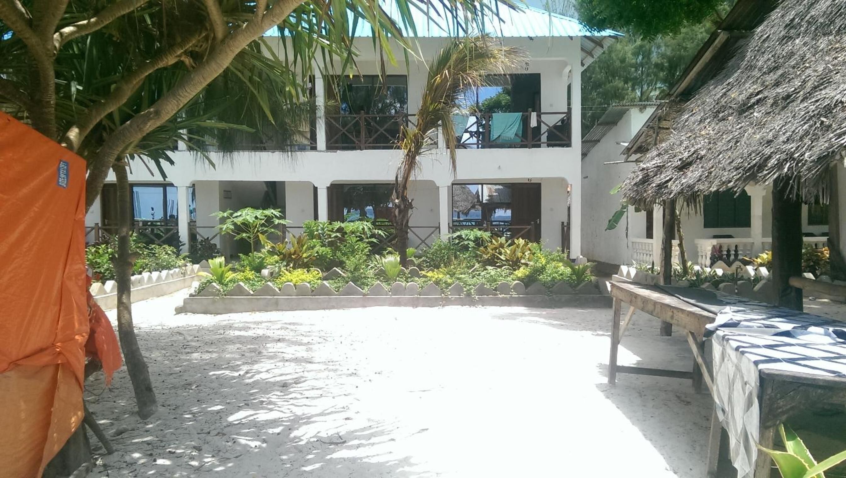 Un patio de hotel con un jardín central, una estructura de techo de paja y una zona de estar cubierta.