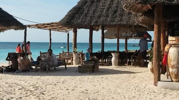 Na praia, areia branca, espreguiçadeiras, guarda-sóis