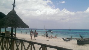 Na praia, areia branca, espreguiçadeiras, guarda-sóis 