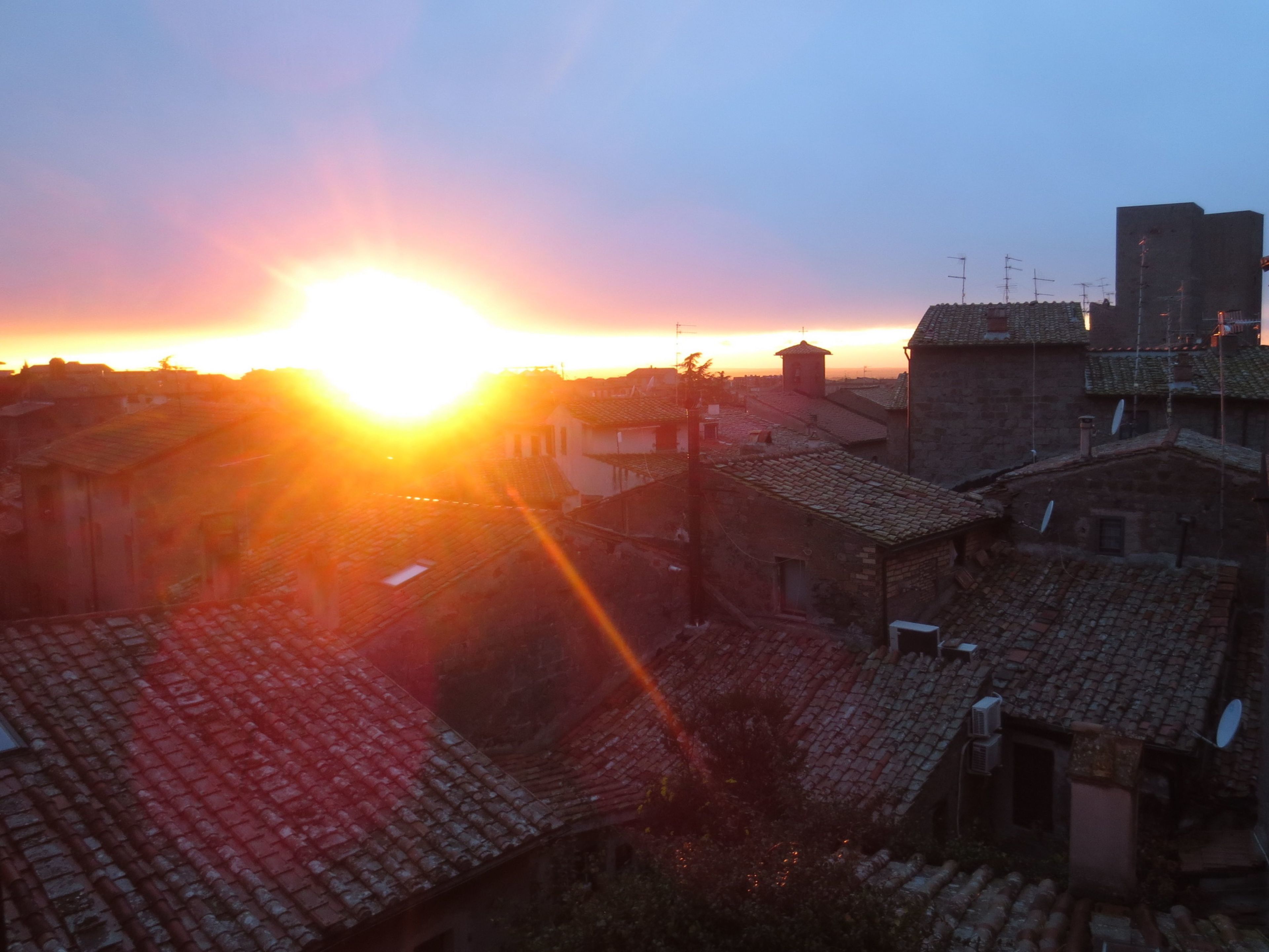 Un atardecer sobre un pueblo con edificios tradicionales y un cielo despejado.