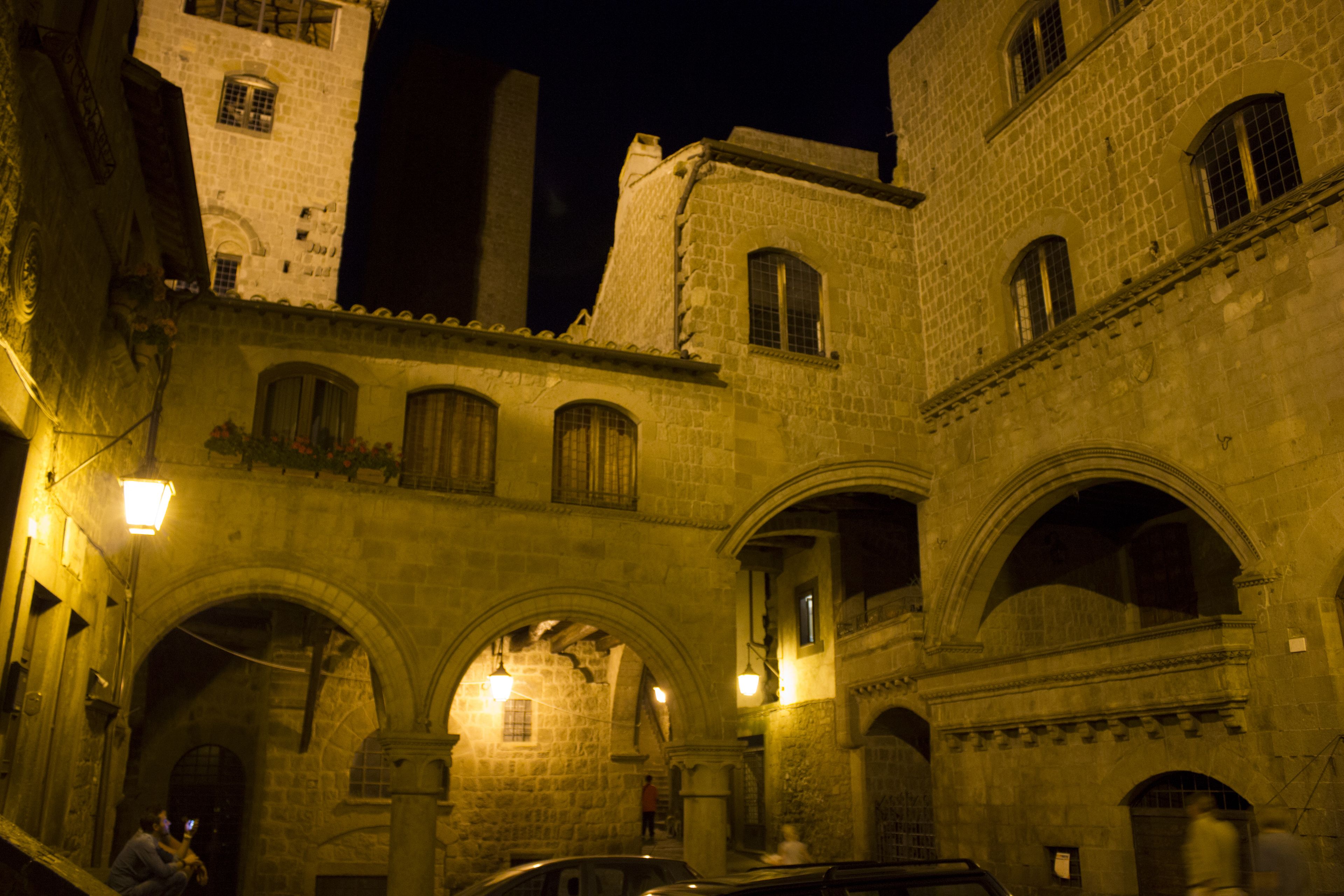 A historic stone building with arched doorways and windows, illuminated by warm lighting.