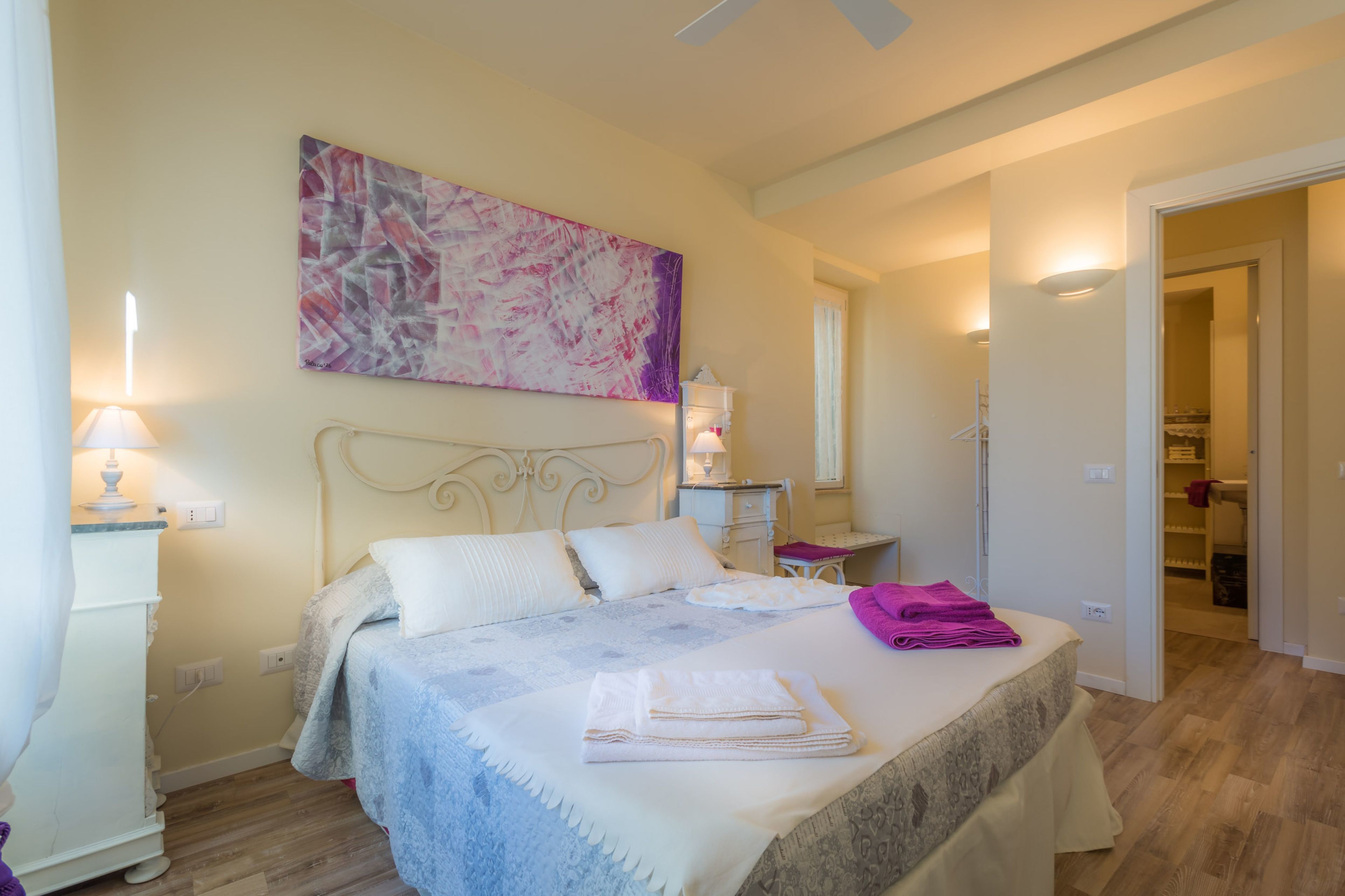A bedroom with a bed, bedside tables, a desk, and a closet.