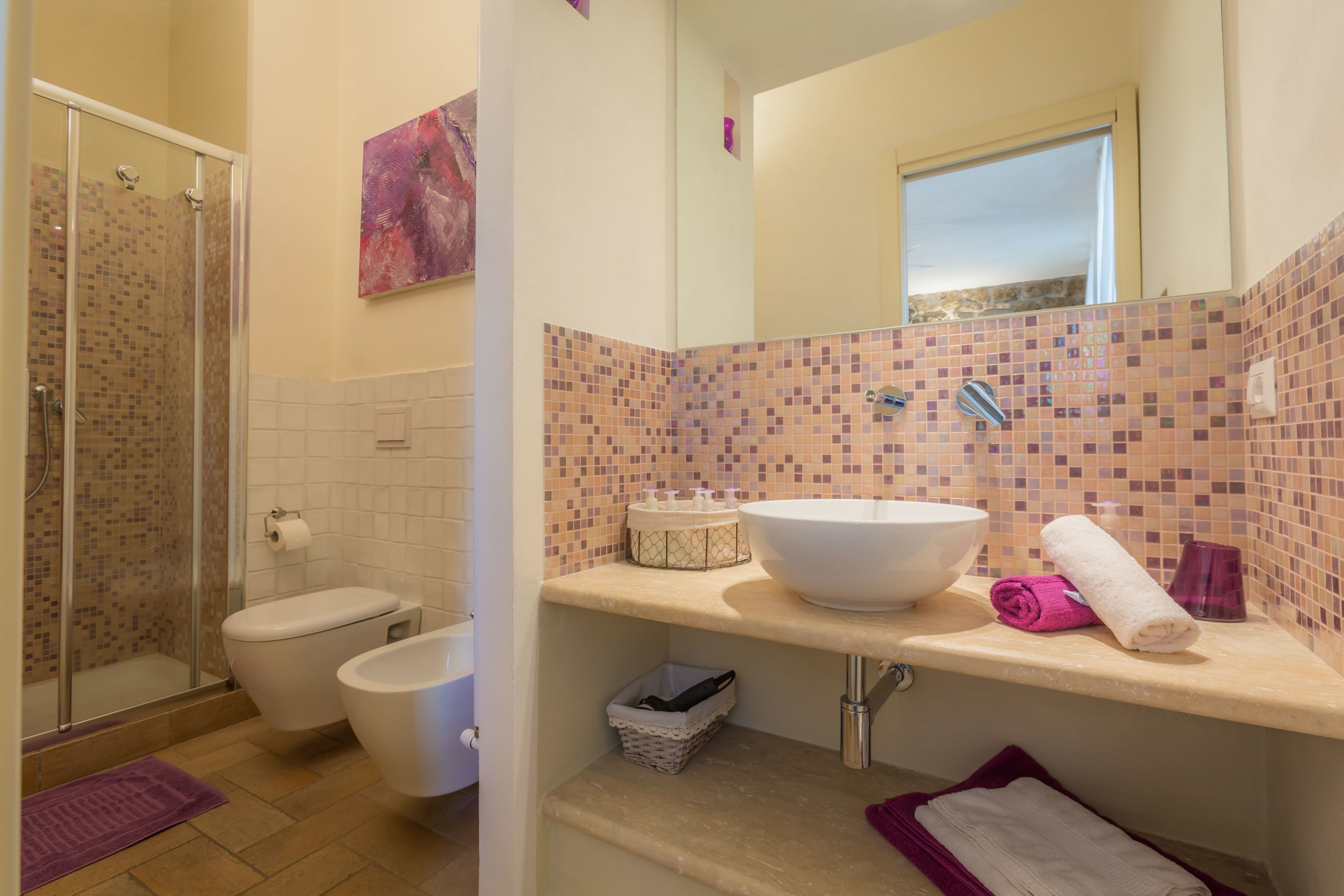 Een badkamer met douche, toilet, wastafel en spiegel.