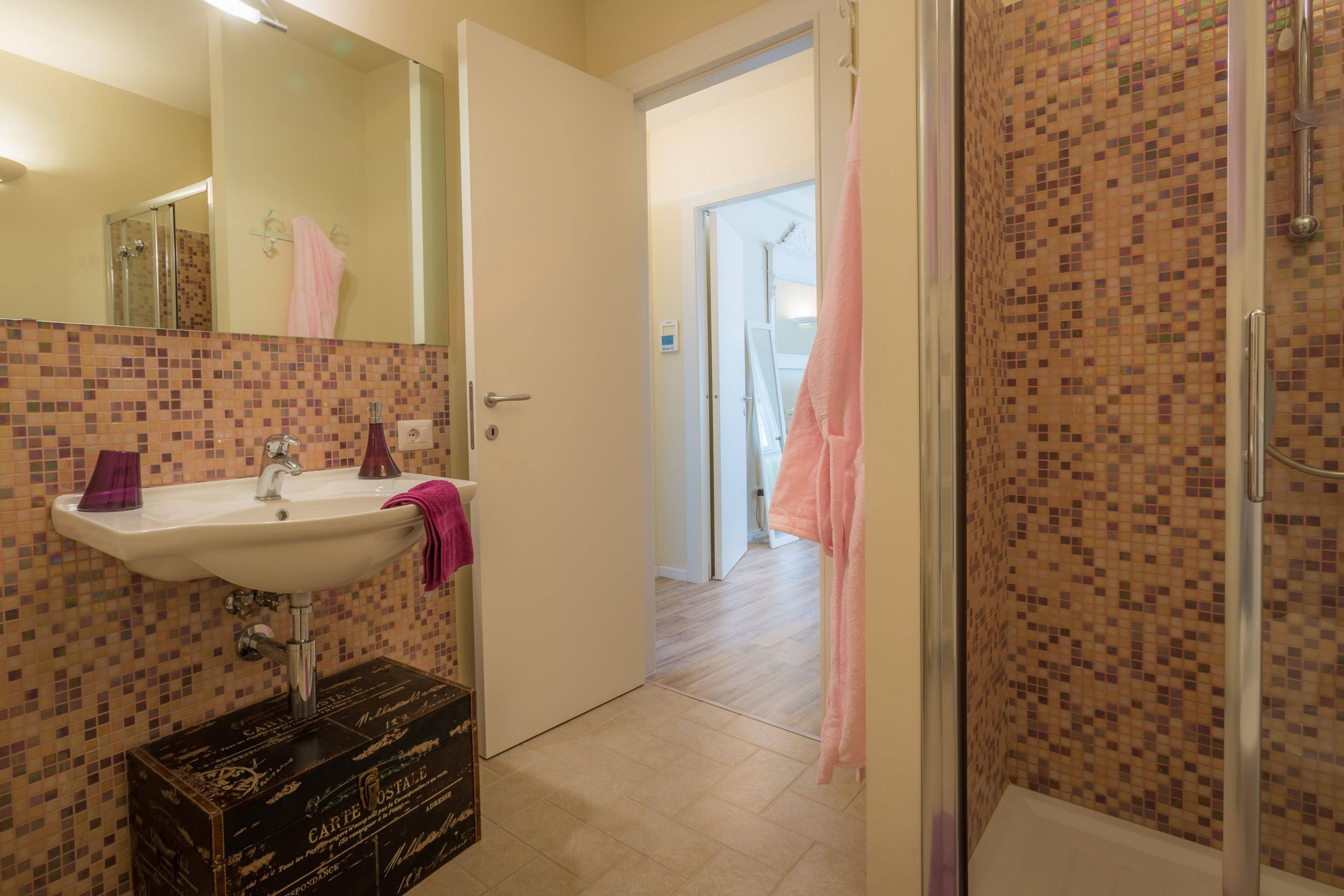 A bathroom with a sink, mirror, and shower area.