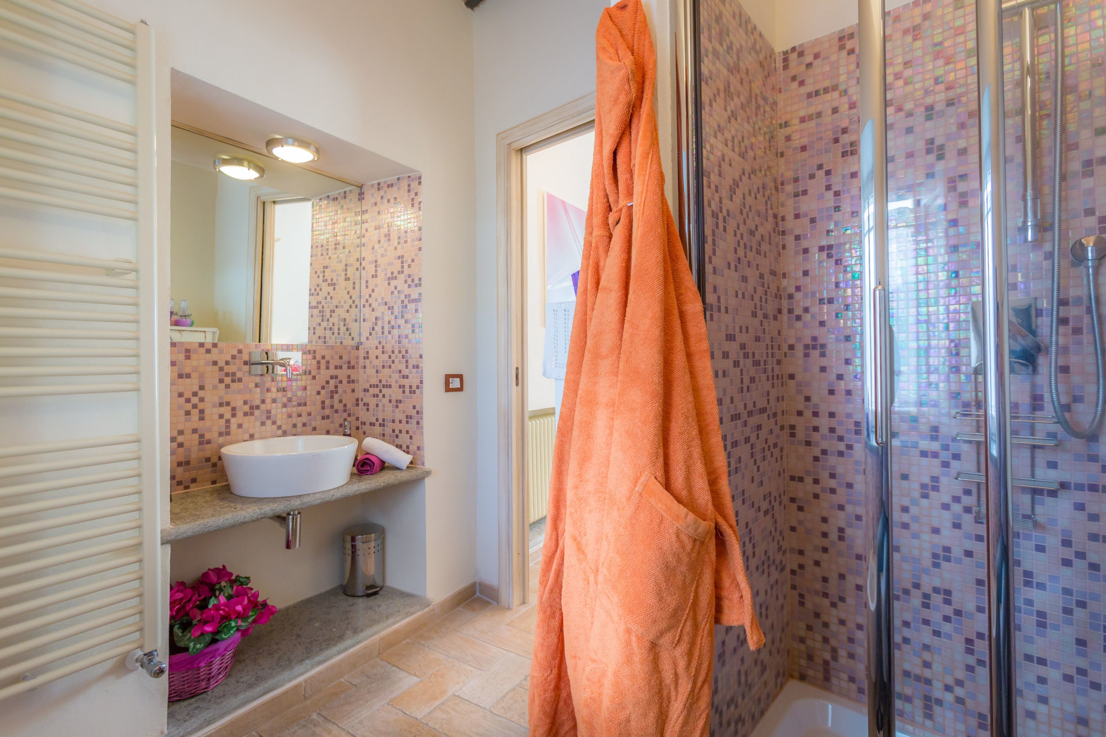 A bathroom with a white sink, a mirror, a shower with a glass door, and a tiled wall.