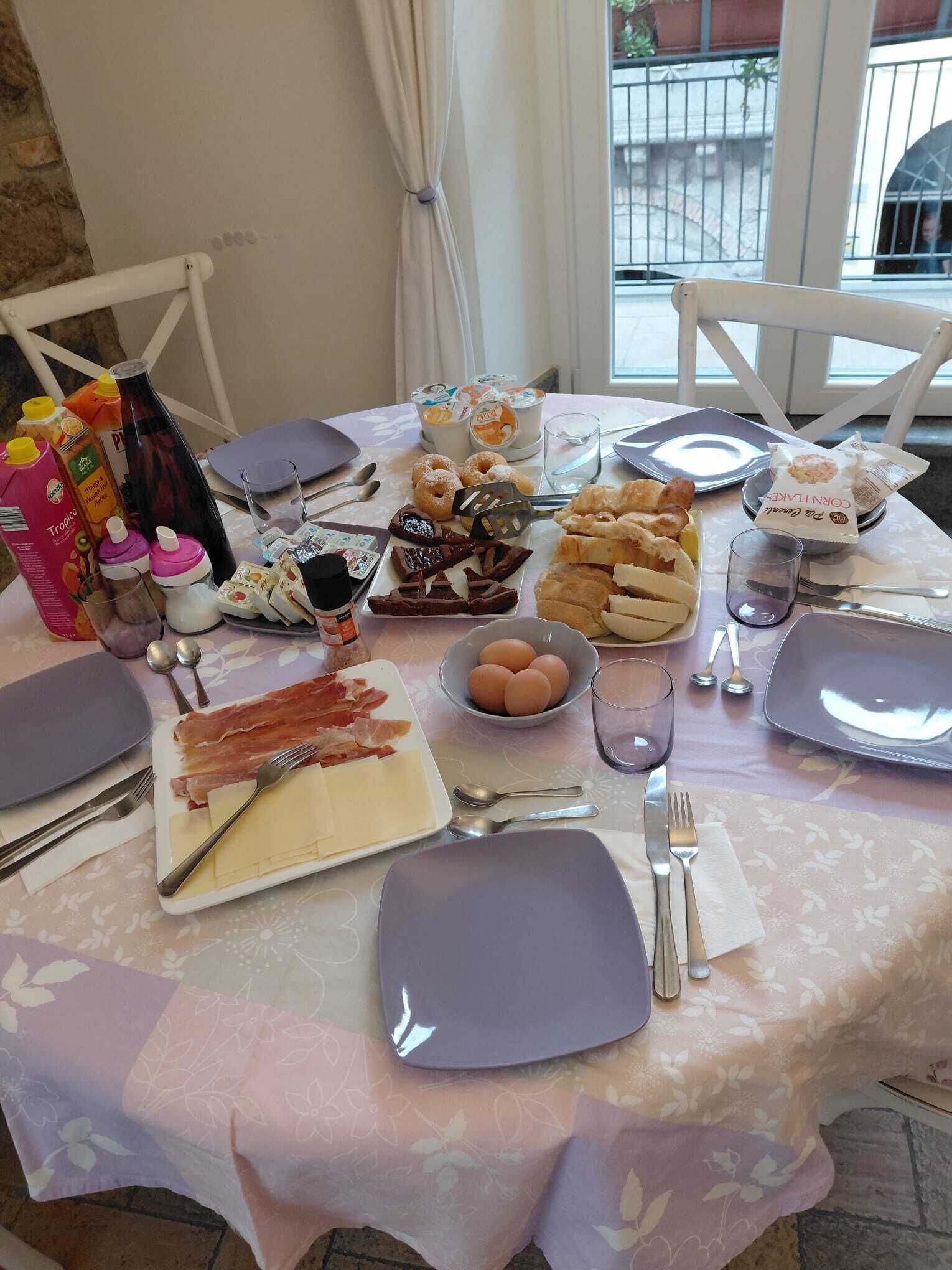 Una mesa de desayuno con diversos alimentos, utensilios y condimentos.
