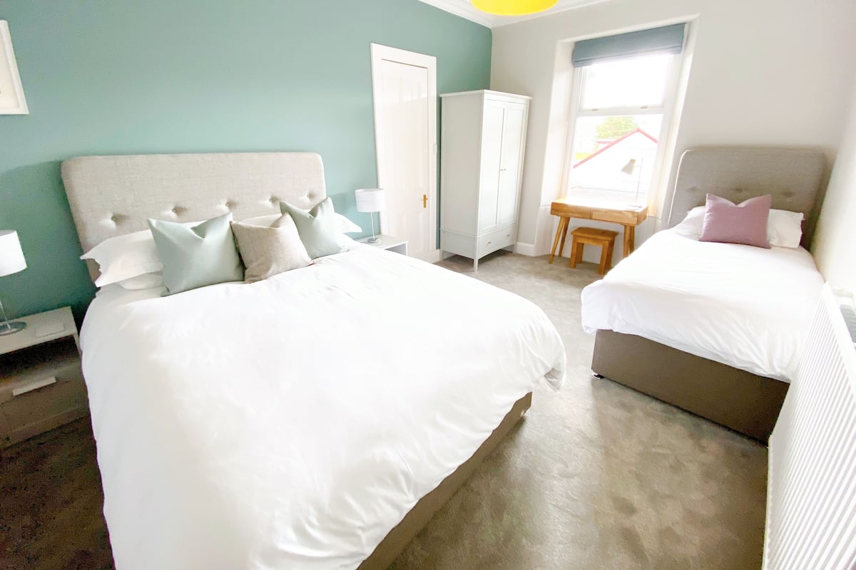 A hotel room with two beds, a wardrobe, a desk, and a window.
