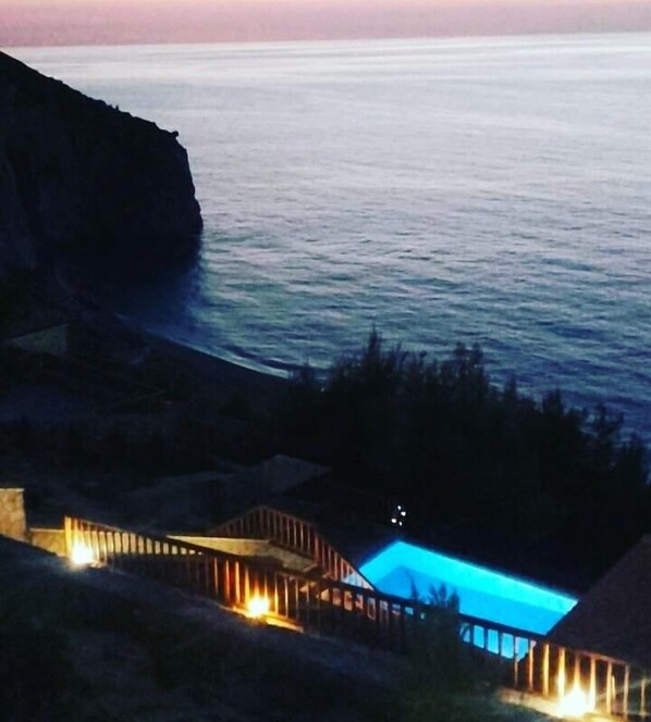A pool area with a view of the ocean at dusk. - Milos Paradise Luxury Villas (Lefkada)