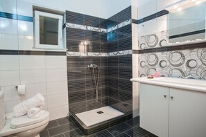 A modern bathroom with a shower, toilet, and sink. - Villa Maria (Paros)