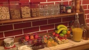 A kitchen counter with various food items and containers, a fruit bowl, and a pitcher of orange juice. - Dunroamin (Aviemore)