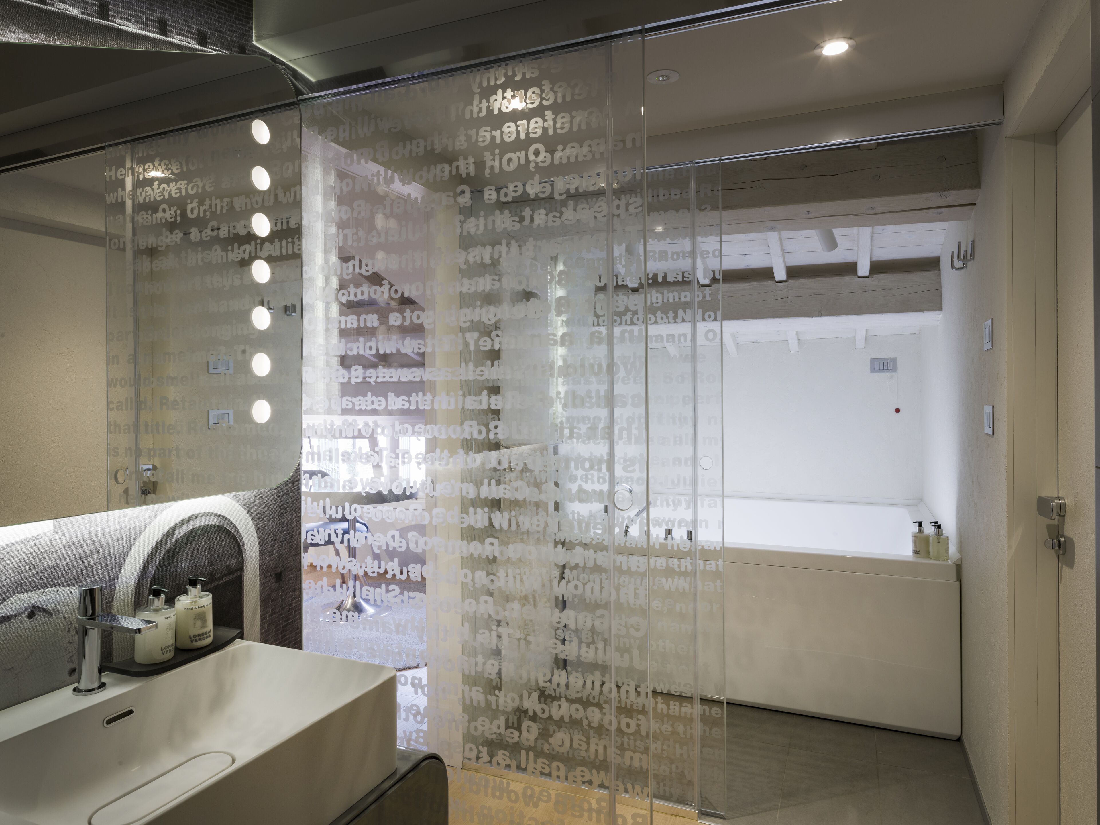 A modern bathroom with a glass partition, a sink with toiletries, and a shower area.
