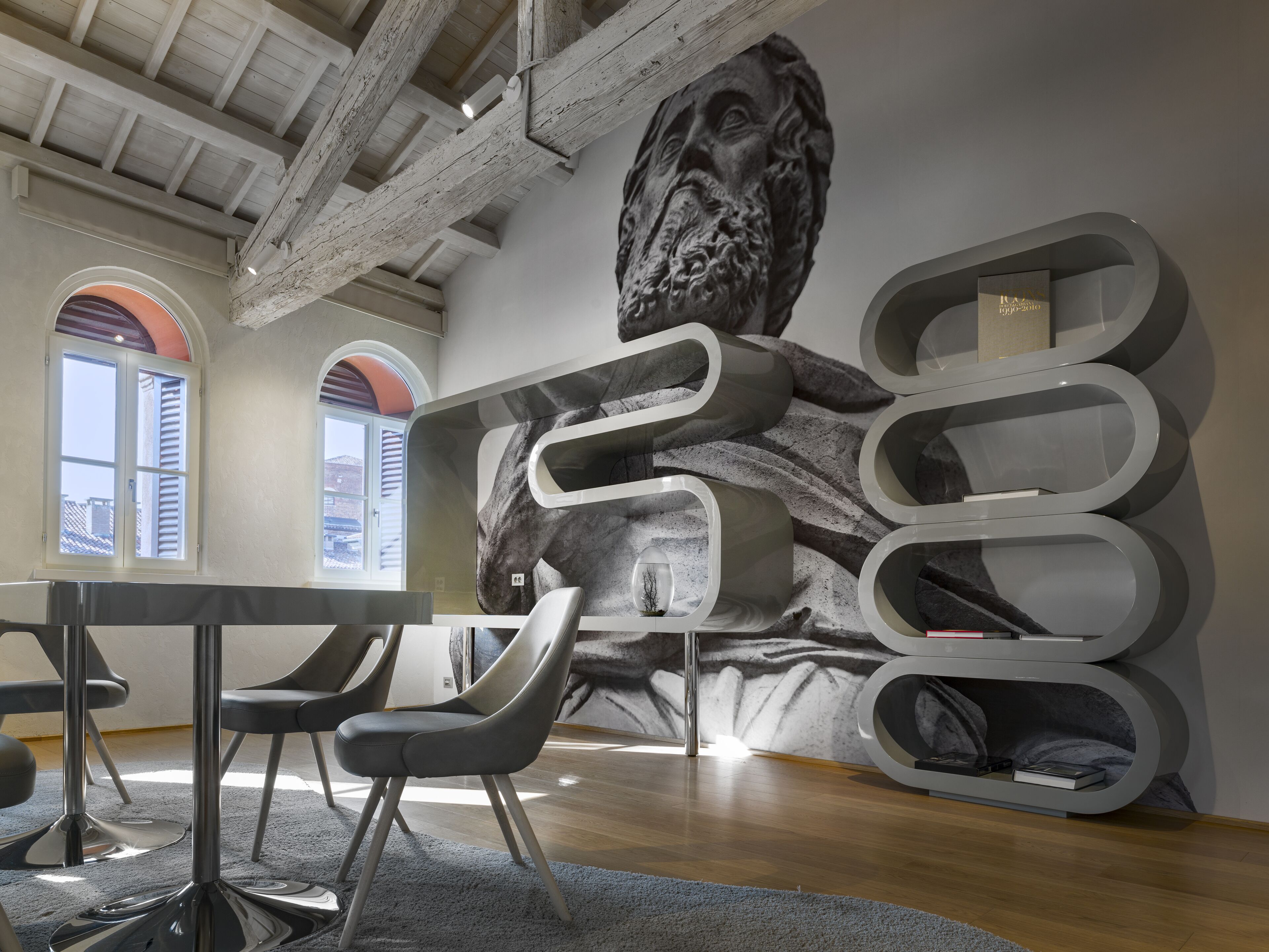 A modern interior with a high ceiling, exposed beams, and a large abstract mural.