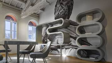 A modern interior with a high ceiling, exposed beams, and a large abstract mural.