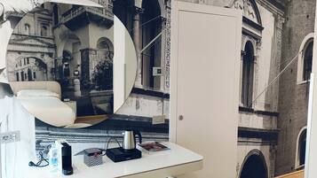 Una habitación con un escritorio blanco, una silla blanca, un espejo grande y un mural en la pared que muestra detalles arquitectónicos.