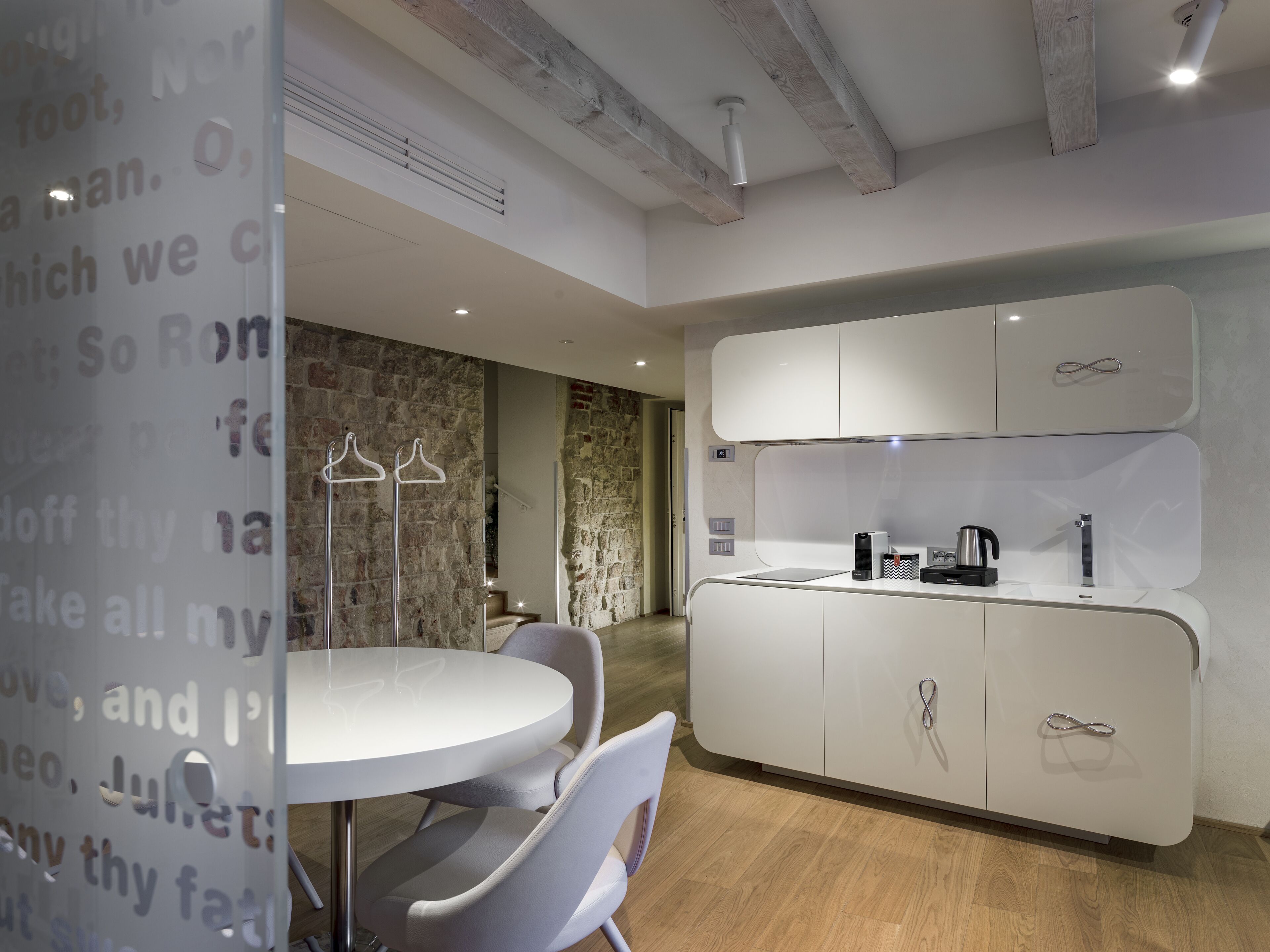 A modern kitchen with white cabinets, a built-in oven, and a coffee maker.