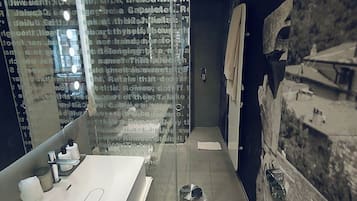 A modern bathroom with a large mirror, a white sink, and a glass shower enclosure.