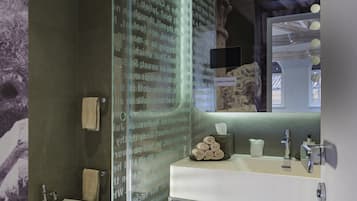 A modern bathroom with a glass shower enclosure, a freestanding bathtub, and a vanity with a mirror.