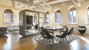 Une pièce spacieuse avec un haut plafond en bois, un grand miroir et un coin repas doté de chaises et d’une table au design moderne.