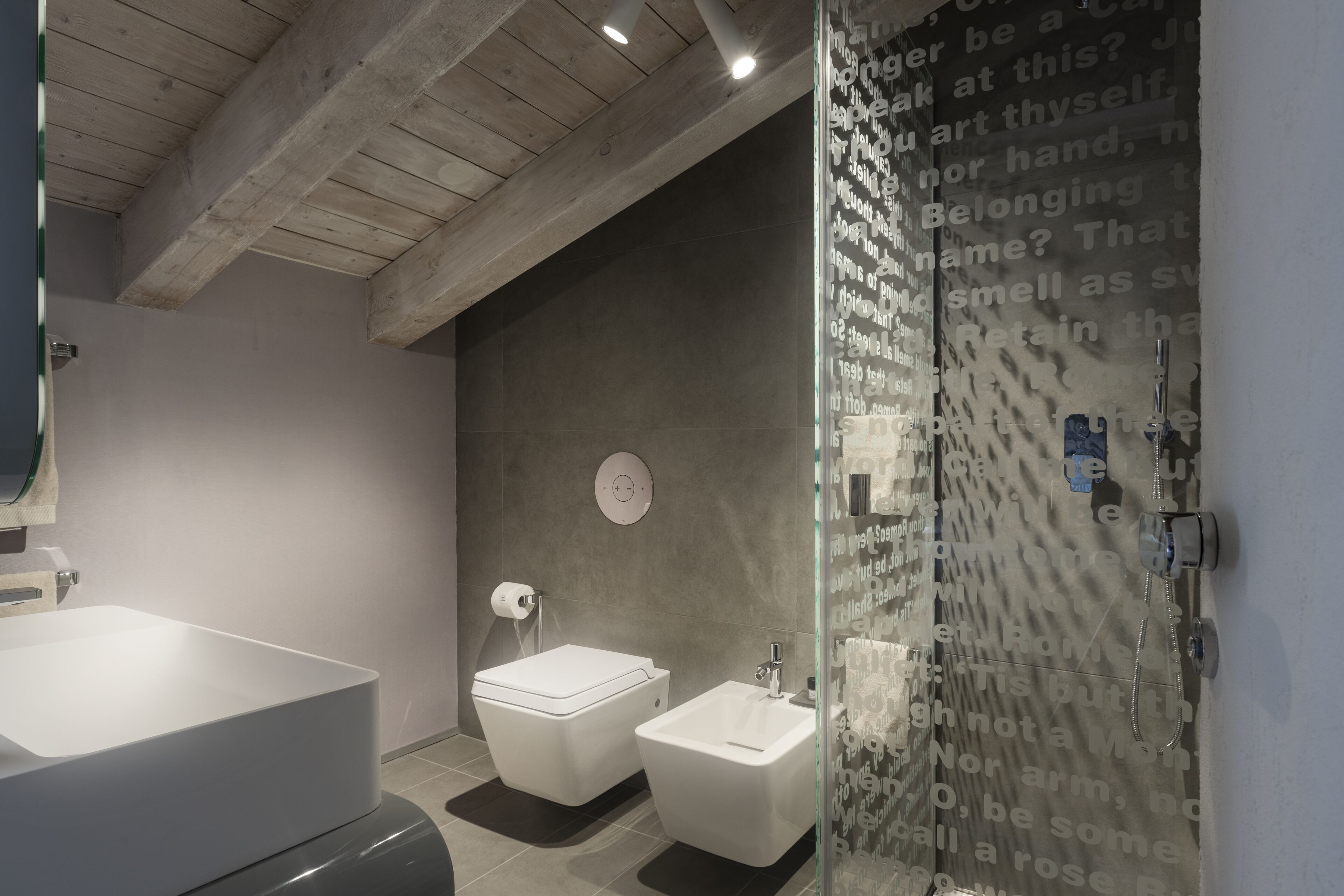 A modern bathroom with a large white bathtub, a toilet, and a bidet.