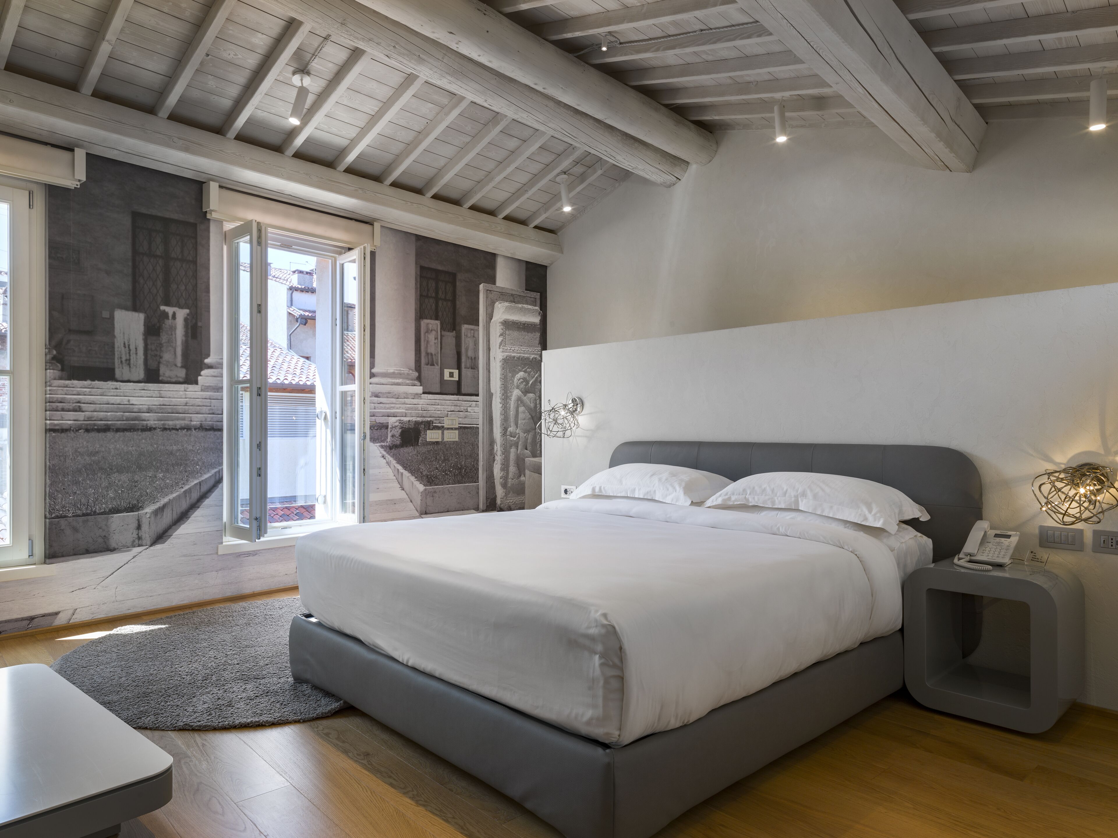 Un dormitorio moderno con una cama grande, una mesita de noche y vistas a un espacio exterior.