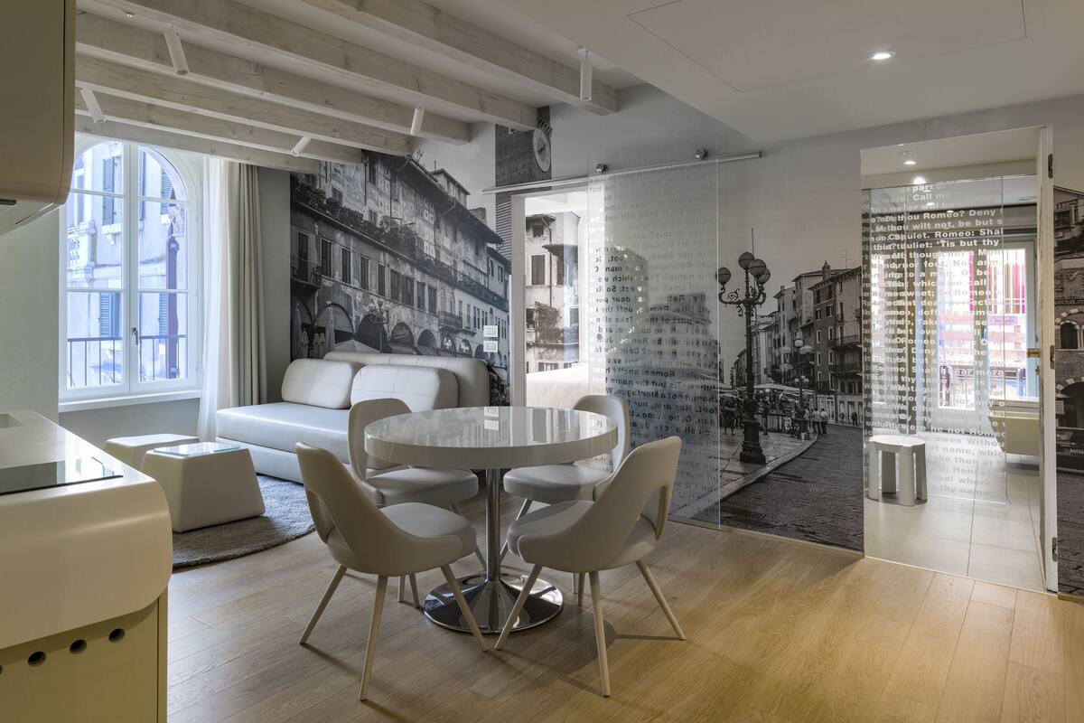 A modern interior with a round table, white chairs, a sofa, and a mural of a cityscape.