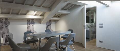 Una sala de conferencias moderna con techo alto, vigas a la vista y una gran mesa con cuatro sillas.