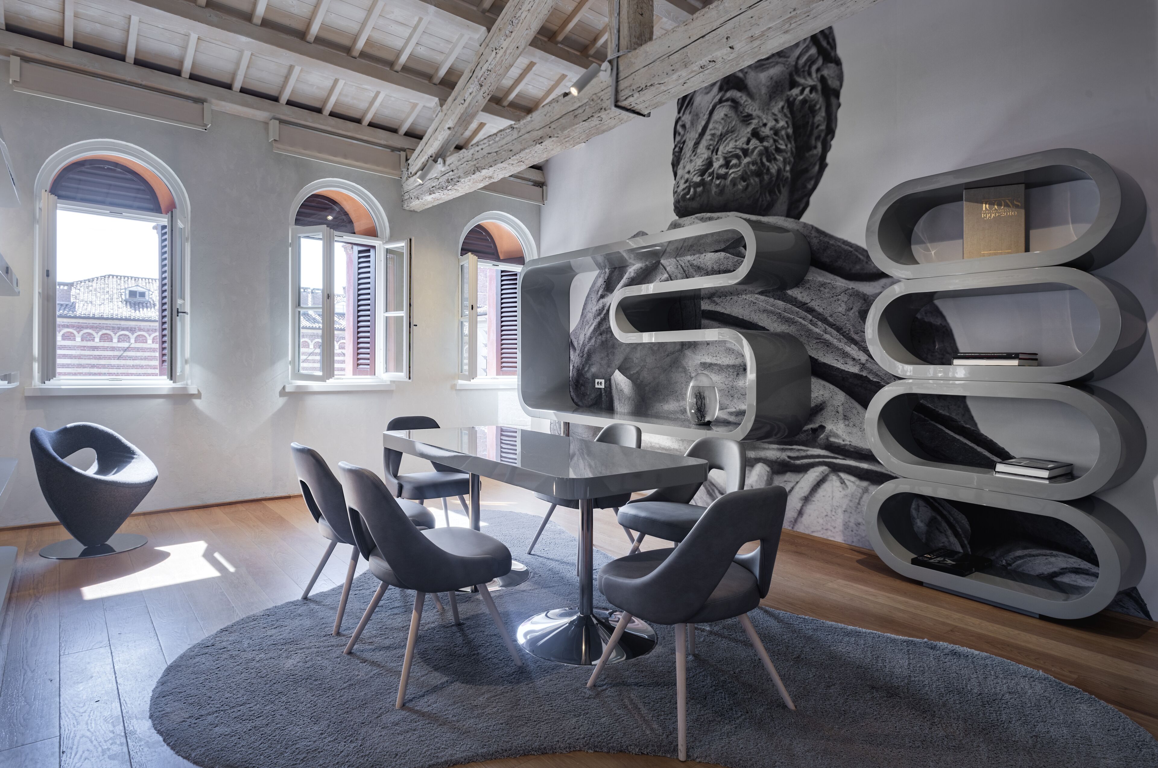 A modern interior with a round table, black chairs, and a large abstract wall art piece.