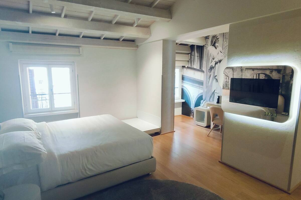 A modern bedroom with a bed, a TV, and a desk.
